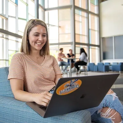 Female student studying on laptop in building